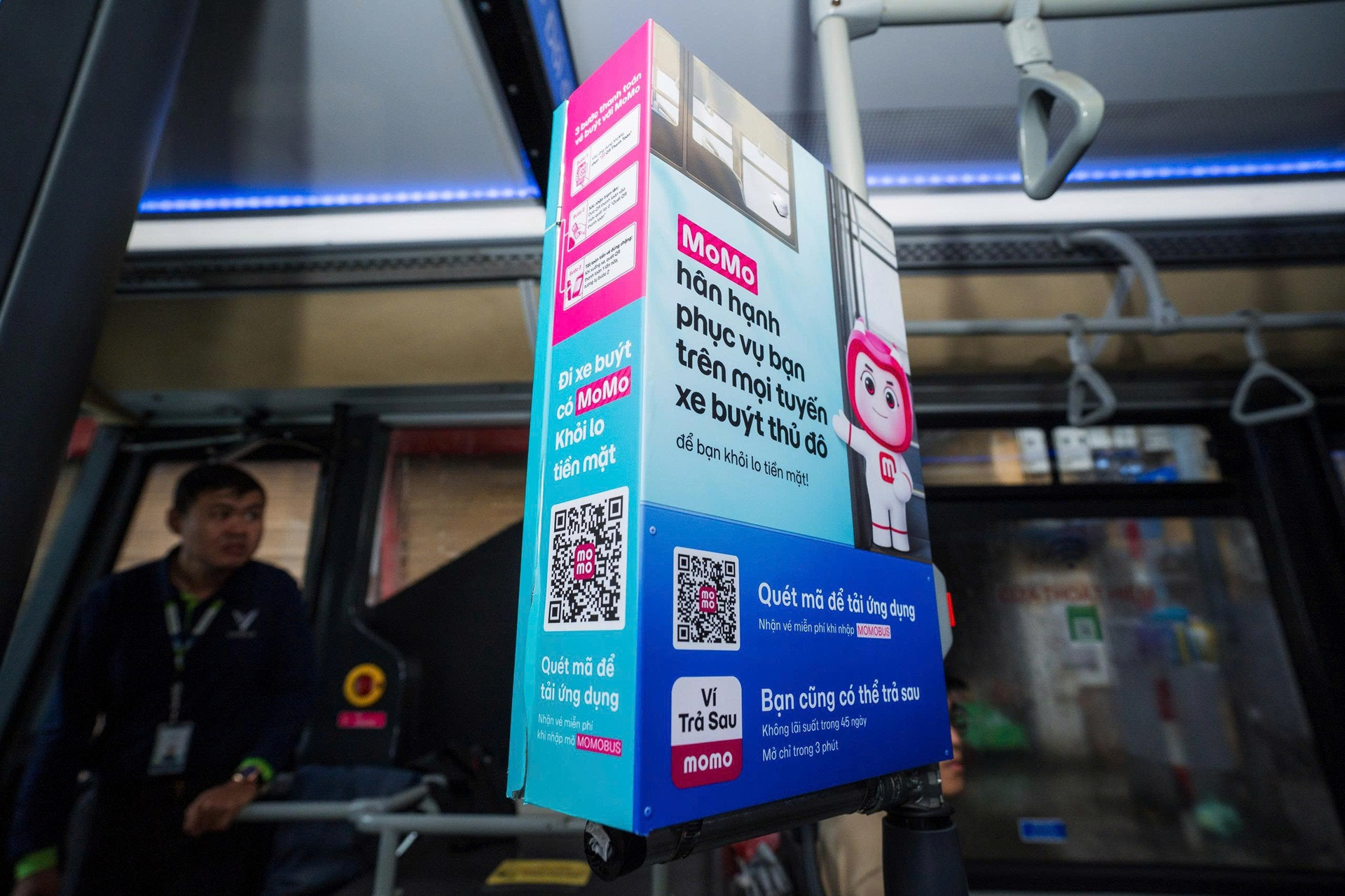 Photograph of a MoMo-branded installation inside a bus, showing the deployed campaign display and surrounding bus interior.